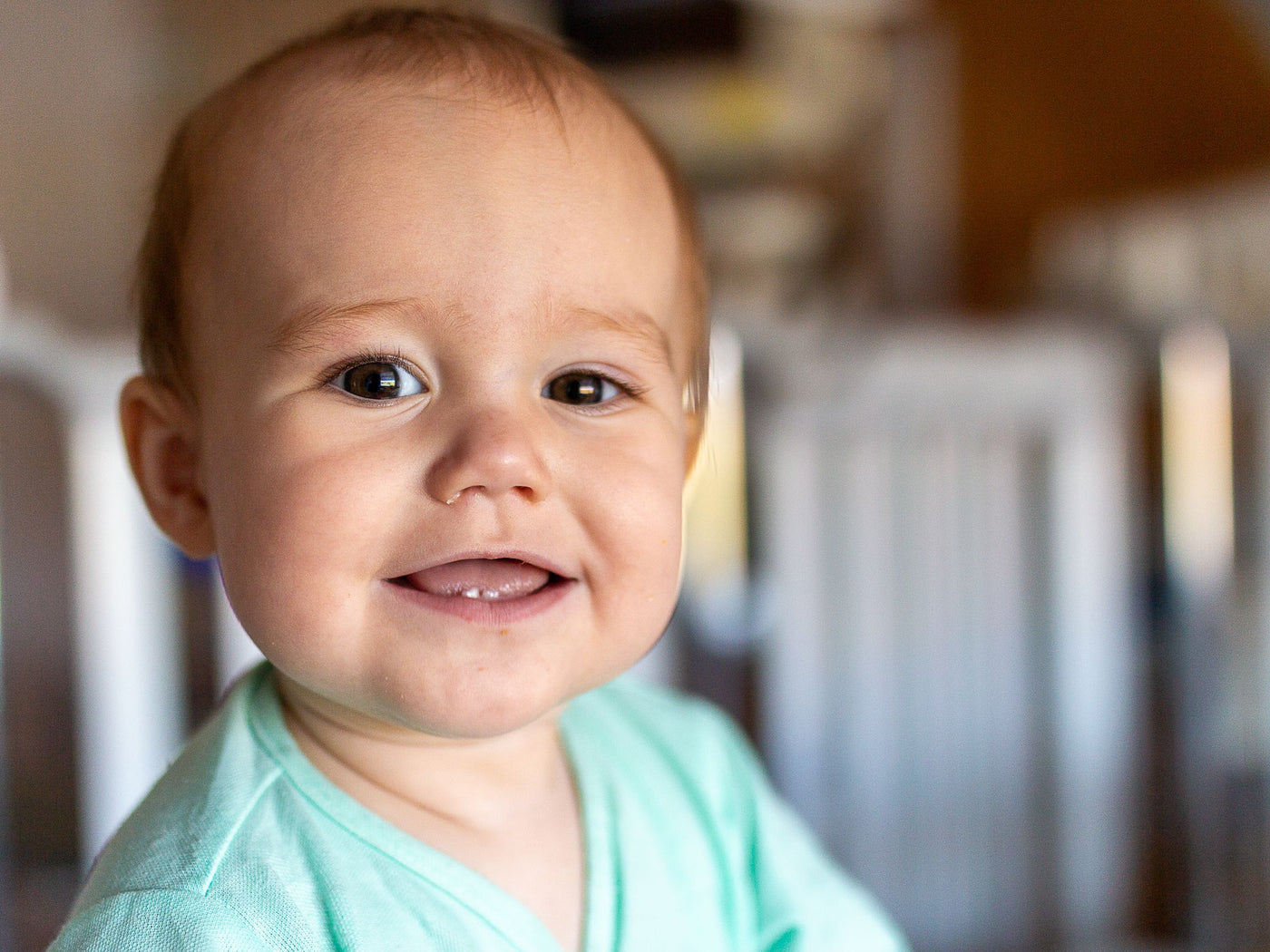 Lachende baby met de eerste doorkomende tandjes in de onderkaak